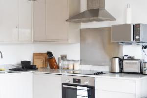 a kitchen with white cabinets and a stove top oven at 1Bed Gem, Quick Access to Windsor, Central London in Slough +12 photos