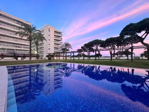 a swimming pool with palm trees and a building at Apartamento Casa Gallardo in Blanes