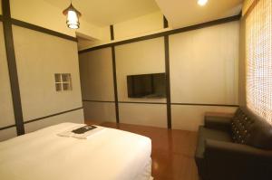 a room with a bed and a couch and a tv at Hananoi Bed and Breakfast in Hengchun