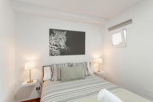 a white bedroom with a bed with two lamps at Casa Alejandro in Firgas