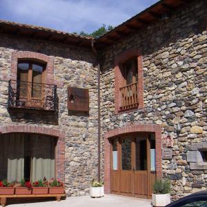 a stone building with a wooden door and a balcony at Hotel Rural CHOUSA VERDE in Vegacervera