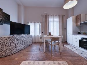 a kitchen with a table with chairs and a television at Albachiara Apartment in Lampedusa