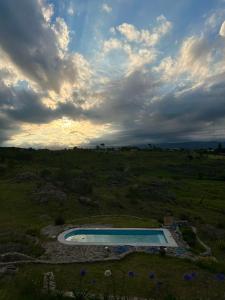 a swimming pool in a field with a cloudy sky at Cabañas Casa Flor Yacanto in Villa Yacanto +17 photos