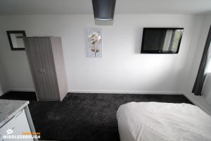 a bedroom with a bed and a tv on a wall at Jayden House in Middlesbrough