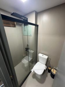 a bathroom with a toilet and a glass shower at Beach Haus beira mar bessa in Tambaú