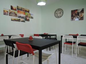 una sala da pranzo con tavoli, sedie e un orologio sul muro di The Pillohouzzze a Malacca