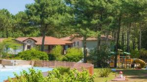 une maison avec une aire de jeux devant une cour dans l'établissement Maison charmante à Lacanau avec piscine partagée et terrasse, à Lacanau