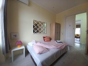 a bedroom with a bed with pink sheets and a window at Ergzotic Apartments & Room in Sombor