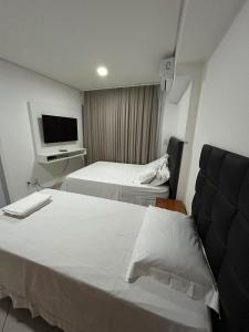 um quarto de hotel com duas camas e uma televisão em Landscape Beira Mar Fortaleza em Fortaleza