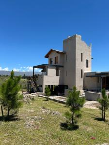 a house in the middle of a field with trees at Cabañas Casa Flor Yacanto in Villa Yacanto