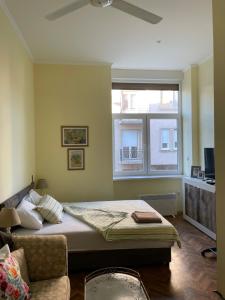 a bedroom with a bed and a couch and a window at Ergzotic Apartments & Room in Sombor