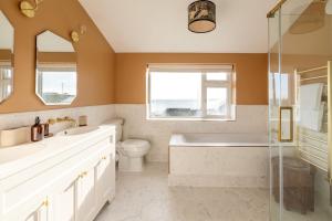 a bathroom with a tub and a toilet and a sink at Luxury Cornish Seaview Bungalow in Looe +13 photos