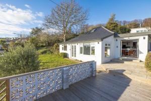 a white house with a fence on a deck at Luxury Cornish Seaview Bungalow in Looe