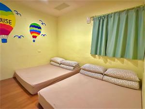 a room with two beds and a balloon mural on the wall at One House in Gongliao