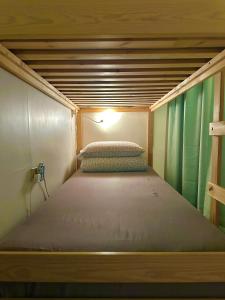 a bed in a tiny house with a light on it at One House in Gongliao