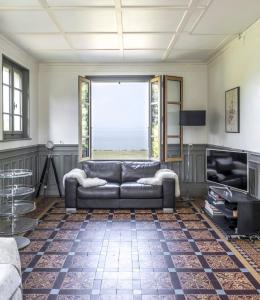 a living room with a couch and a large window at Maison de Maître au bord du lac in Excénevex