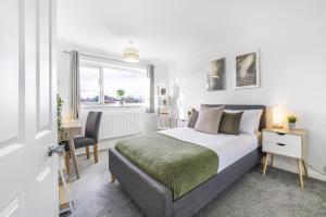 Un dormitorio con una cama y un escritorio y una ventana. en 4 Bedroom Elegant House Near Peterborough City Center with Free Parking - Angus Suites by Contractor Lettings, en Peterborough