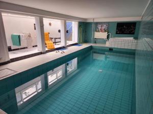 a large swimming pool with blue tiles in a room at Villa Casa Blanca mit Privatem Schwimmbad 26 grad und Sauna in Duisburg