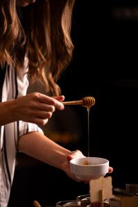 a woman holding a bowl of food with a chopstick at Athenian Riviera Hotel& Suites in Athens
