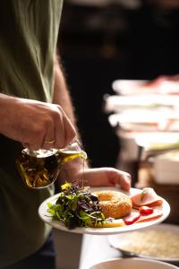 a person is pouring oil on a plate of food at Athenian Riviera Hotel& Suites in Athens