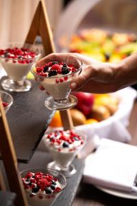 a person is reaching for a dessert in martini glasses at Athenian Riviera Hotel& Suites in Athens