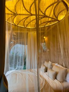 a bedroom with a canopy bed with white pillows at Wahem Eco Bamboo - Wahem Tebenan in Ubud
