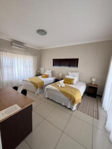 a hotel room with two beds and a desk at Cora's Boutique Bed & Breakfast in Swakopmund