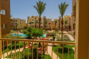 - Balcón con vistas a un complejo con piscina y palmeras en Go Egypt Apartments Inside Karma Beach Resort North Al Ahiaa , Hurghada, en Hurghada