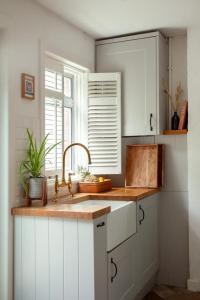 a kitchen with white cabinets and a sink and a window at The Cycling Cottage, Surrey Hills AONB, Dorking in Dorking