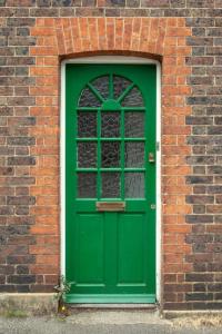 a green door in a brick wall with a window at The Cycling Cottage, Surrey Hills AONB, Dorking in Dorking +20 photos