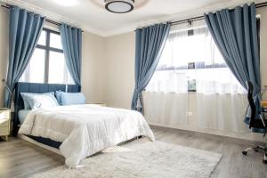 a bedroom with blue curtains and a bed with a rug at K's Place in Accra