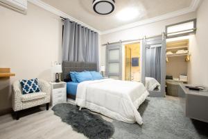 a white bedroom with a bed and a chair at K's Place in Accra