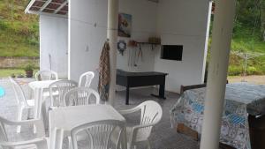 a room with white chairs and a table and a television at Sitio São Francisco de Assis in São Pedro de Alcântara +17 photos