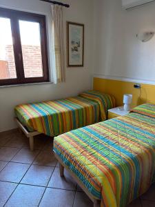 Una habitación de hotel con dos camas y una ventana. en Villa Pinna, en San Teodoro