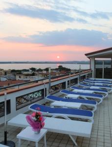 una fila de mesas en un balcón con vistas a la puesta de sol en Hotel Resort Il Panfilo, en Lago Patria