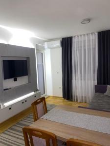 a room with a bed and a table with a television at Apartman Filip in Kruševac +13 photos