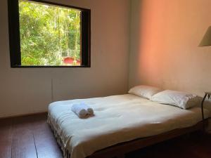 a bed with a towel on it in a room with a window at Pouso in Paraty