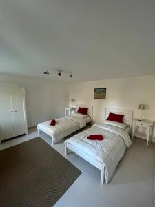 two beds in a white room with red pillows on them at Holiday home with alpine panorama in Teolo +39 photos