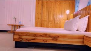 a bedroom with a wooden bed with white pillows at Evelina House in Boma la Ngombe