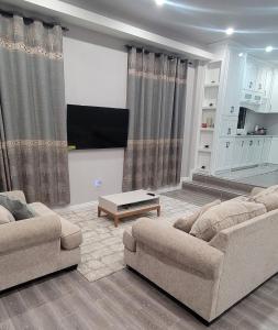 a living room with two couches and a flat screen tv at The Royal Haven Herstelling GY in Nismes