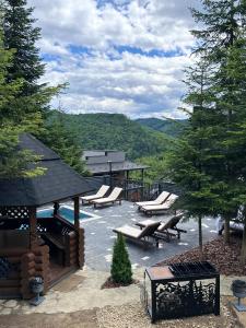 eine Gruppe von Bänken auf einer Terrasse mit Bergen im Hintergrund in der Unterkunft VIP HOUSES Карпати Мигово in Myhowe