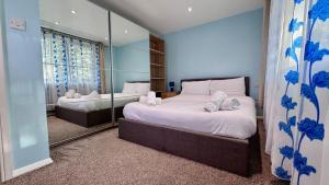 a bedroom with two beds and a mirror at Large Modern Home Near Barking Station With SuperFast 1gbps Wi-Fi & Free Parking in Barking