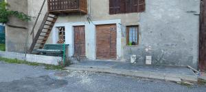 a building with a wooden door and a bench in front at L'Essentiel in Arbusigny