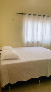 a bedroom with a white bed with a window at Casa de Temporada em Iranduba in Iranduba