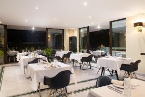 a restaurant with white tables and chairs and windows at Athenian Riviera Hotel& Suites in Athens