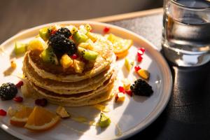 a plate with a stack of pancakes with fruit on it at Athenian Riviera Hotel& Suites in Athens