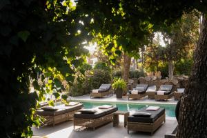 a pool with chaise lounges and lounge chairs next to a pool at Athenian Riviera Hotel& Suites in Athens