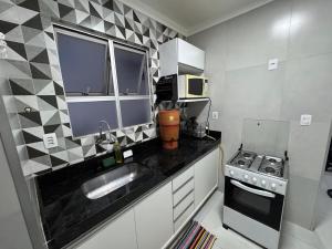 a small kitchen with a sink and a stove at Apartamento Gabriel in Uberaba
