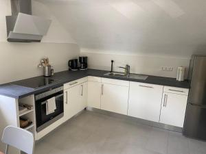 a kitchen with white cabinets and a sink and a stove at City Rooms Tamm in Tamm