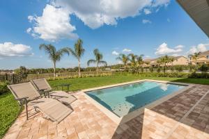 a swimming pool with two lounge chairs next to a yard at Lovely Home With Theme Rooms, Game Room With Waterpark & Resort Access Resort Access At Encore Resort- 7705By in Kissimmee